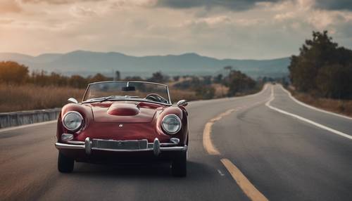 A dashing classic sports car of dark red color speeding down the highway