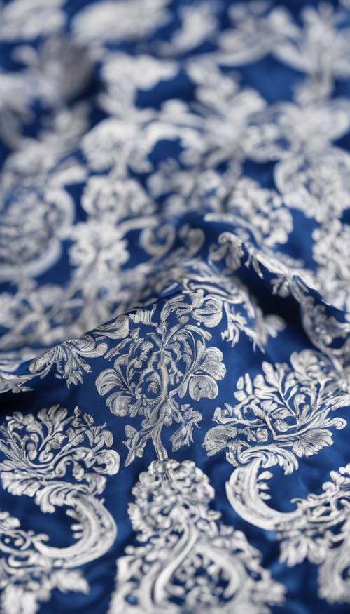 Un gros plan du motif damassé complexe bleu et blanc sur un tissu en soie brillant.