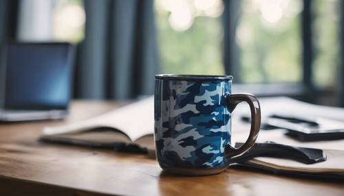 Снимок синей кофейной кружки с камуфляжным дизайном, стоящей на учебном столе.