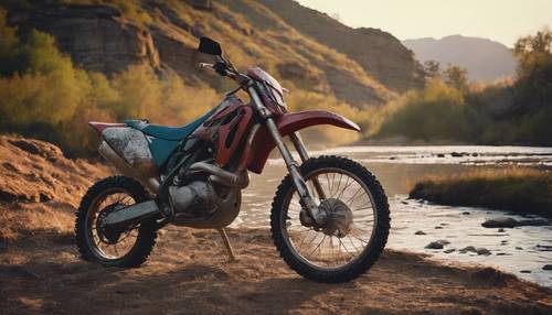 A scenic image of a dirt bike parked beside a tranquil mountain stream at dawn