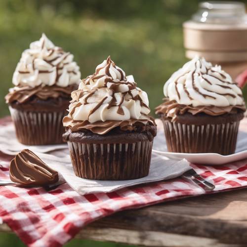Cinco cupcakes com cobertura de chocolate marrom e chantilly de baunilha branca em uma mesa de piquenique