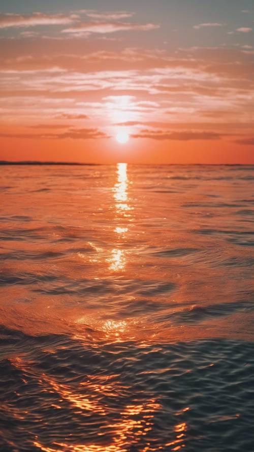 Sole arancione brillante che tramonta su un mare calmo.