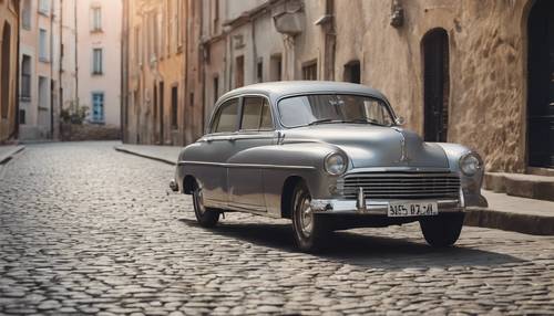 Arnavut kaldırımlı bir caddeye park edilmiş, gümüş jantlı, eski model, lacivert bir araba.