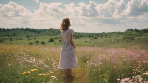 A girl wearing a summer dress standing in a field of blooming wildflowers in July.