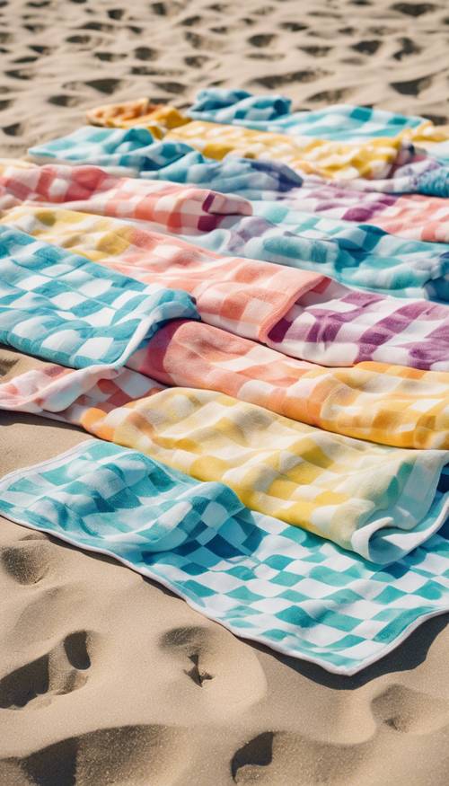 A summer-themed image of checkered pastel beach towels neatly arranged on the sandy shoreline. Tapeet [62782e5d813a4c3597e8]