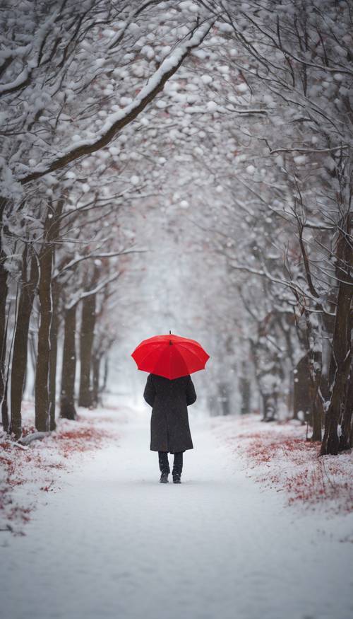 A solitary figure walking on a snow-covered path, holding a bright red umbrella.