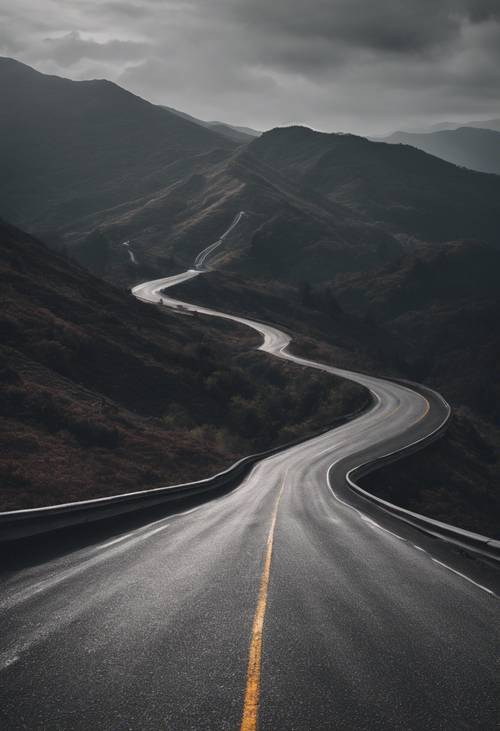 A dark gray textured asphalt road winding through mountains.