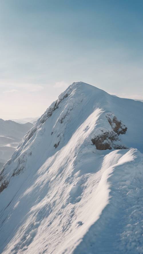 Um pico de montanha branco nevado contra o céu azul claro durante o inverno.