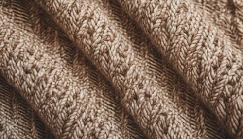 Close up image of a beige herringbone pattern on a woolen fabric.