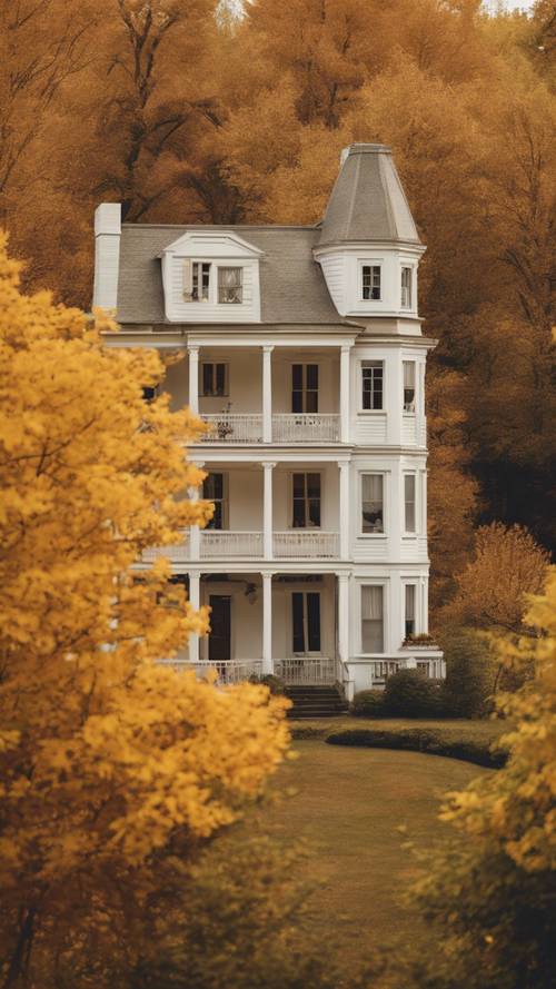 บ้านในชนบทสีขาวที่มีขอบหน้าต่างสีเหลืองตั้งอยู่ท่ามกลางต้นไม้สีฤดูใบไม้ร่วง
