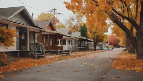 شارع بلدة صغير هادئ وجذاب في الخريف يضم أكواخًا تعود إلى منتصف القرن وأوراق شجر ملونة متساقطة.