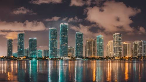 A night scene of Miami's bright-lit skyline mirrored in the calm Biscayne Bay waters.