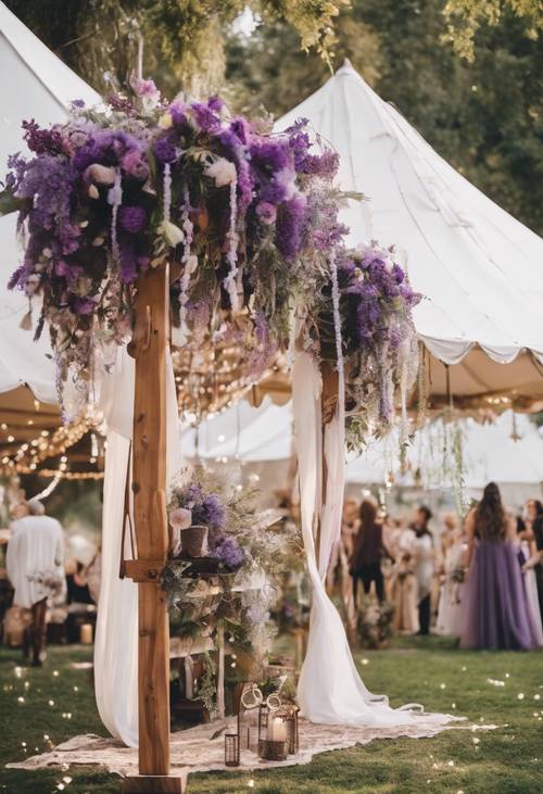 Un mariage en plein air de style bohème avec des fleurs violettes, des attrape-rêves, des tentes blanches et des guirlandes lumineuses.