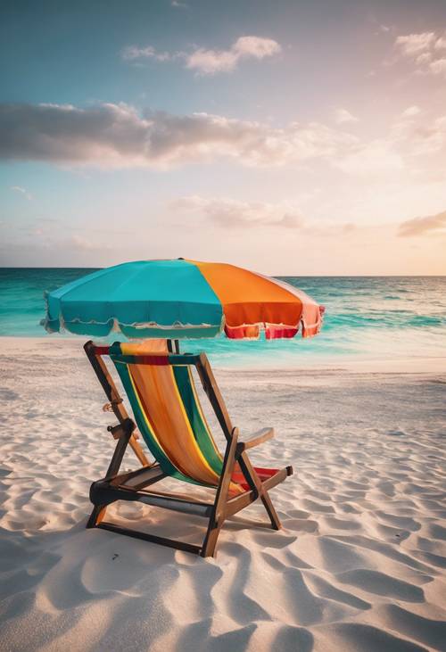 日落时分，白色沙滩上摆放着一张沙滩椅和一把彩色遮阳伞，面朝碧绿的海水。