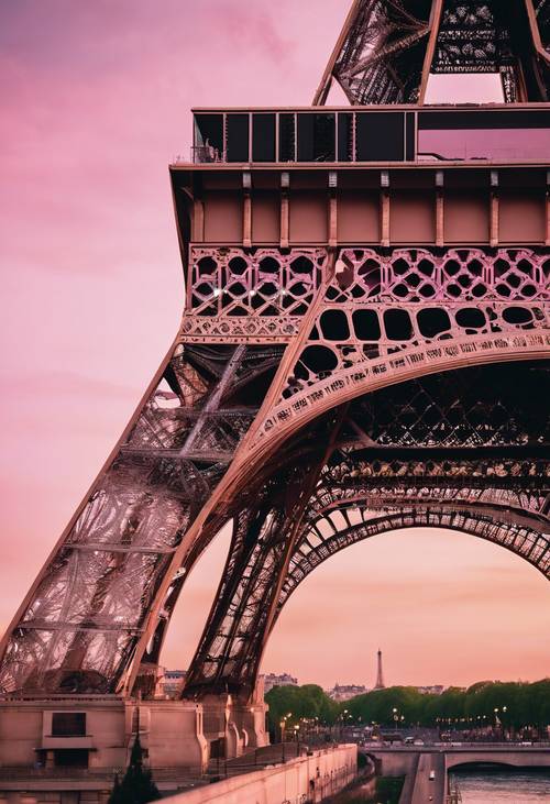 Un primer plano de la intrincada arquitectura metálica de la Torre Eiffel bajo un crepúsculo rosa.