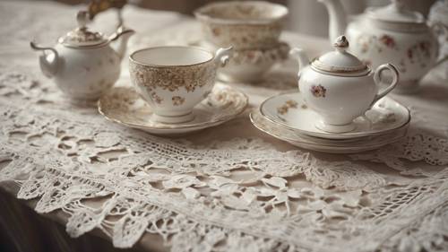 Zbliżenie dekoracji w stylu shabby chic składającej się z antycznego koronkowego bieżnika i delikatnego porcelanowego serwisu do herbaty.