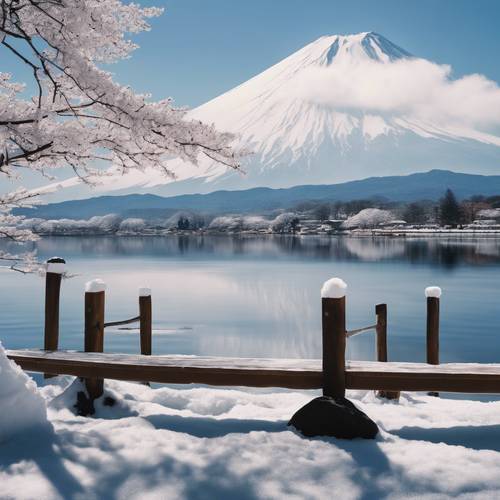 Uma vista panorâmica do Monte Fuji coberto de neve branca, com um calmo e reflexivo Lago Kawaguchiko em primeiro plano.