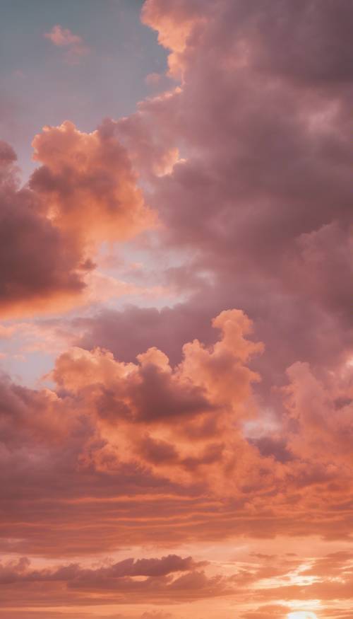 부드러운 햇빛에 의해 오렌지색과 핑크색으로 물든 푹신한 구름과 고요한 일몰.