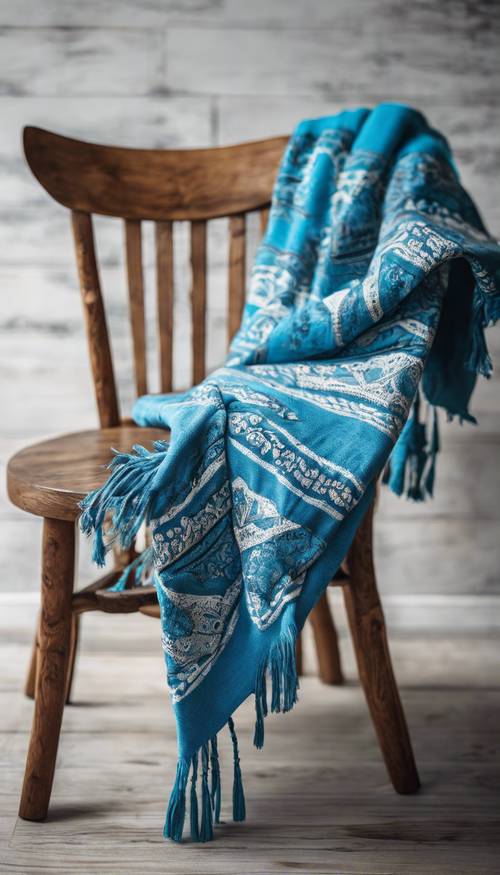Uma manta azul brilhante com padrões boho espalhada sobre uma cadeira de madeira de carvalho.
