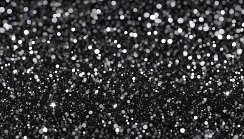 Minuscole particelle di glitter grigio scuro densamente sparse su uno sfondo nero creano un motivo glamour e senza soluzione di continuità.