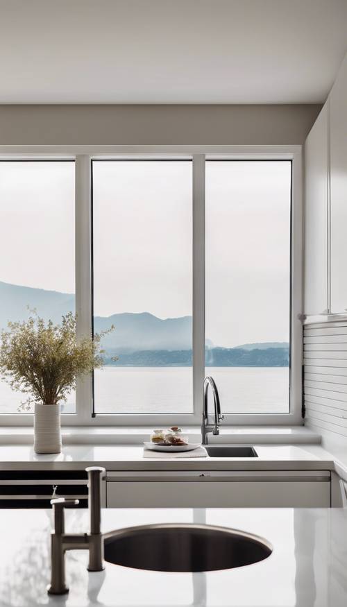 Eine helle und minimalistische moderne Küche mit eleganten weißen Schränken, Geräten aus Edelstahl und einem großartigen Blick auf das Wasser durch das Fenster.