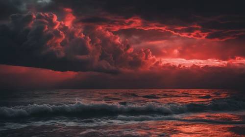 A dramatic red and black sunset over the ocean with storm clouds gathering