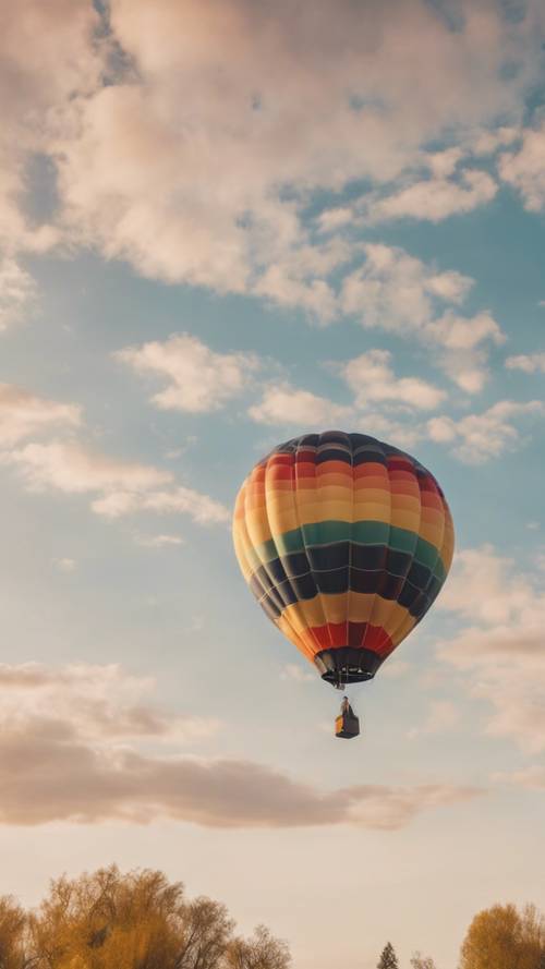 A multi-coloured hot air balloon soaring in the bright morning sky.