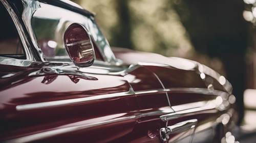 Koyu, zengin bir bordoya boyanmış, 1960&#39;lardan kalma parlak klasik bir arabanın yakından görünümü.