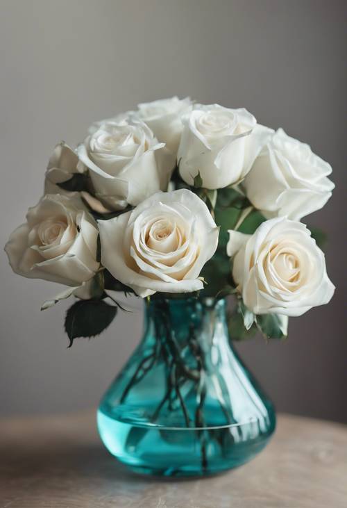 Ramos de rosas blancas y turquesas en un delicado jarrón de cristal.