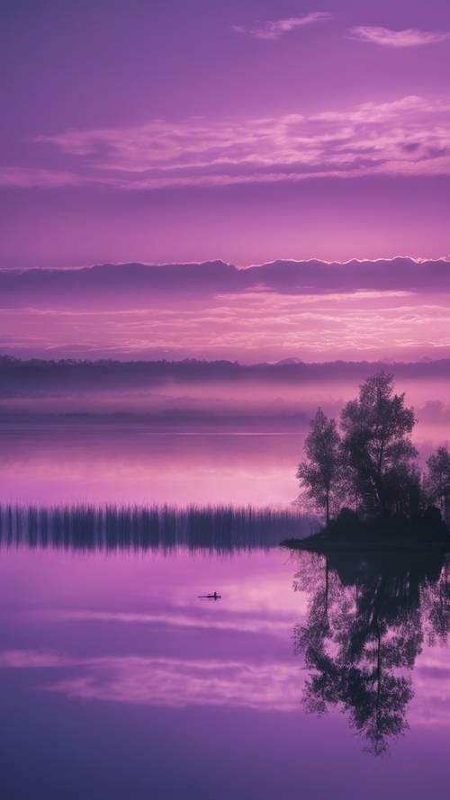 Una serena vista matutina de un vasto lago bajo un cielo púrpura azulado con el horizonte iluminado lentamente por los primeros rayos del día.