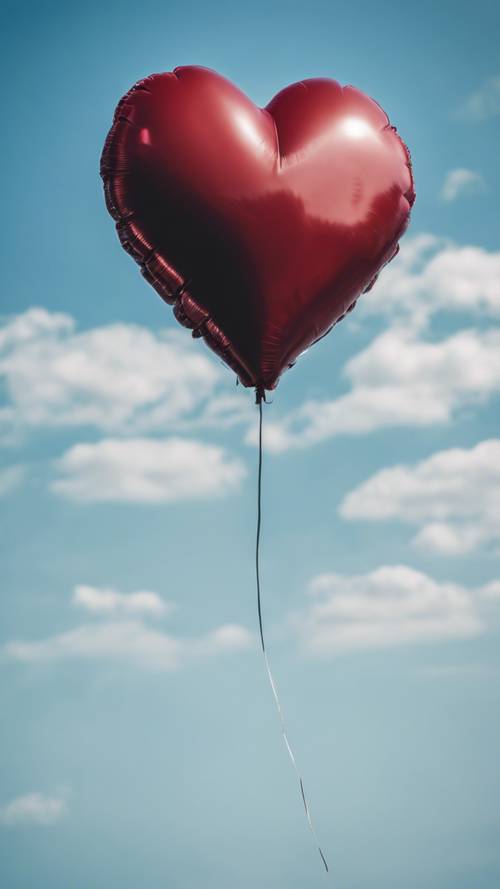 Gambar fotografi balon berbentuk hati berwarna merah dan hitam yang menjulang tinggi di langit biru cerah.