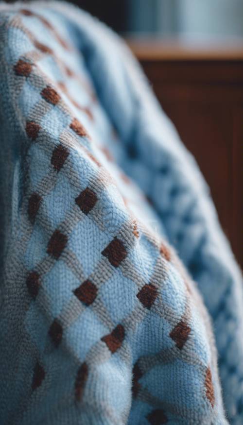 Nahaufnahme eines adretten hellblauen Argyle-Pullovers, der über einem Stuhl hängt.