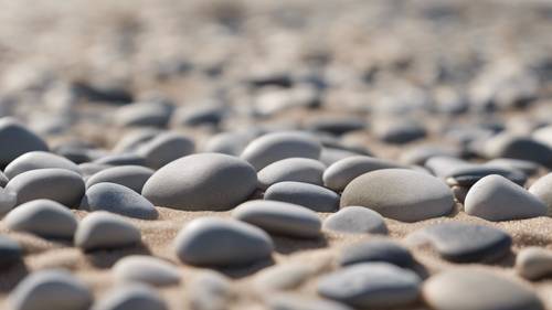 A collection of light gray pebbles arranged in an intricate pattern on a sandy beach.