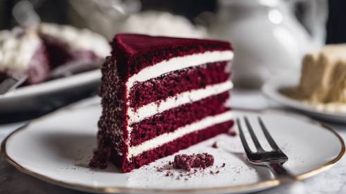 A slice of maroon velvet cake on a dainty porcelain plate with a silver cake fork.