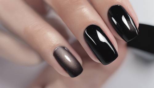 Una mano cuidada con esmalte de uñas negro ombre.