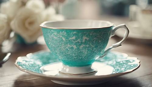 Una taza de té vintage con un patrón de damasco turquesa sobre un platillo blanco.