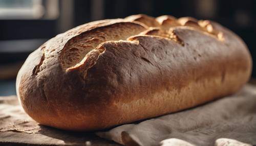 Une miche de pain frais mettant en valeur sa croûte bronzée et sa texture causée par la cuisson.