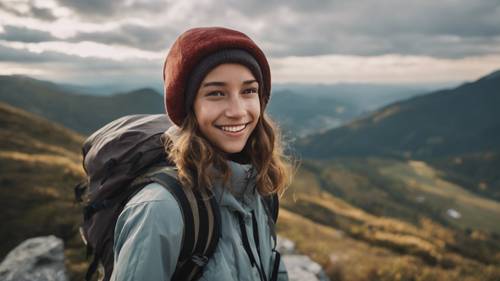 Yürüyüş teçhizatlı genç bir kız bir dağın zirvesinden kameraya gülümsüyor.