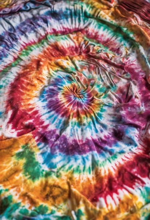A coiled white shirt being saturated with vibrant multi-colored dyes for a tie-dye. Tapet [cde5a71695a445439bc0]