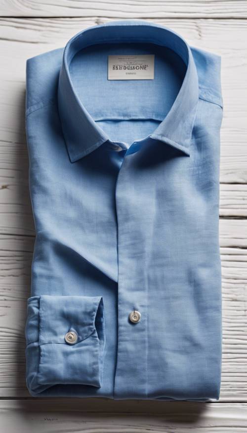 Uma camisa de linho azul, cuidadosamente dobrada, sobre uma mesa de madeira branca.