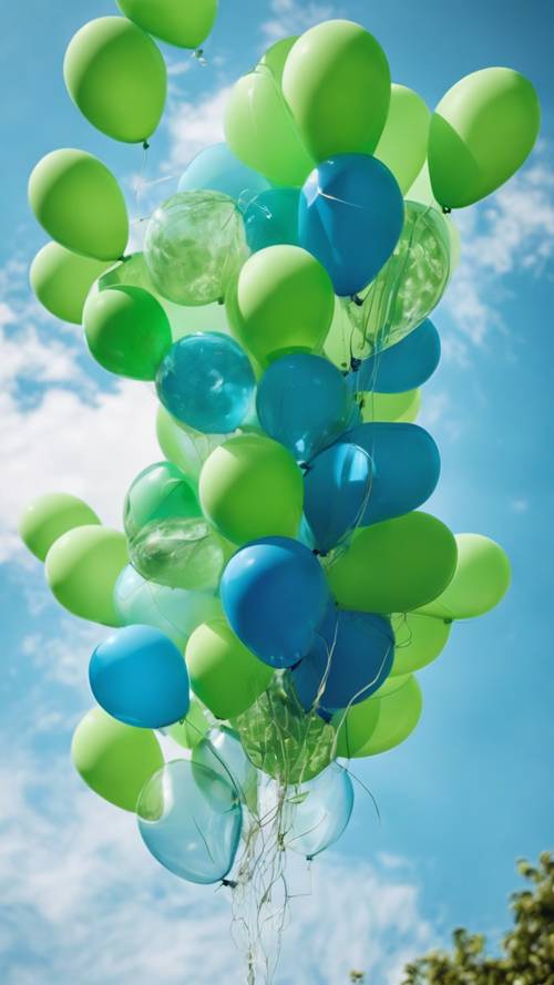 An array of blue and green balloons floating in a clear sky during the day.