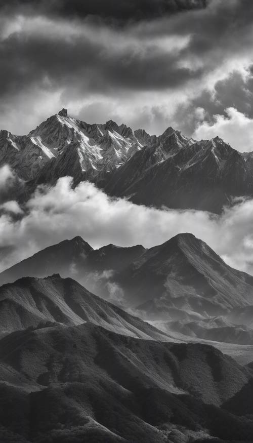 Une image monochrome d’une vaste chaîne de montagnes sous un ciel nuageux.