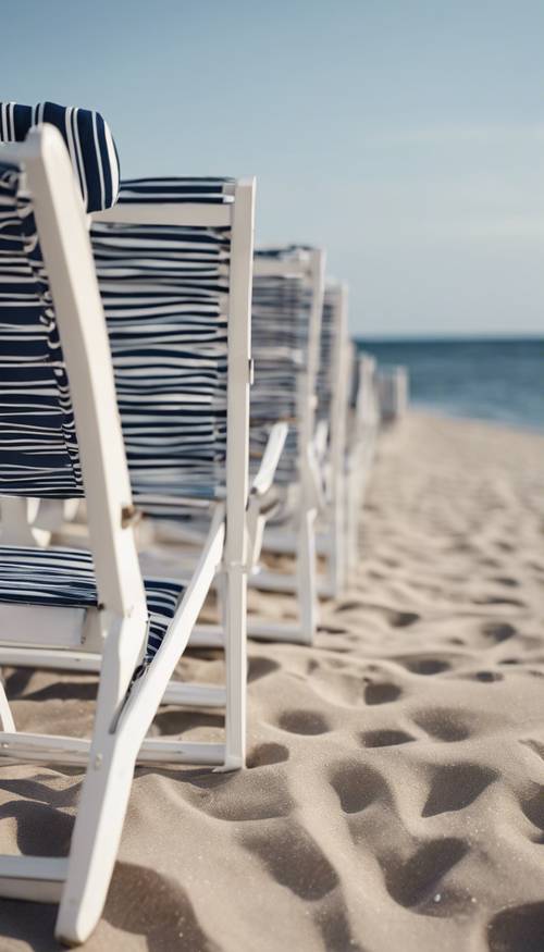 Un gruppo di sedie da spiaggia preppy a strisce blu navy e bianche allineate sulla riva dell&#39;oceano la sera.