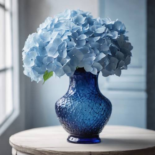 白色木桌上放着一个优雅的蓝色绣球花花瓶，里面盛满了新鲜的绣球花。