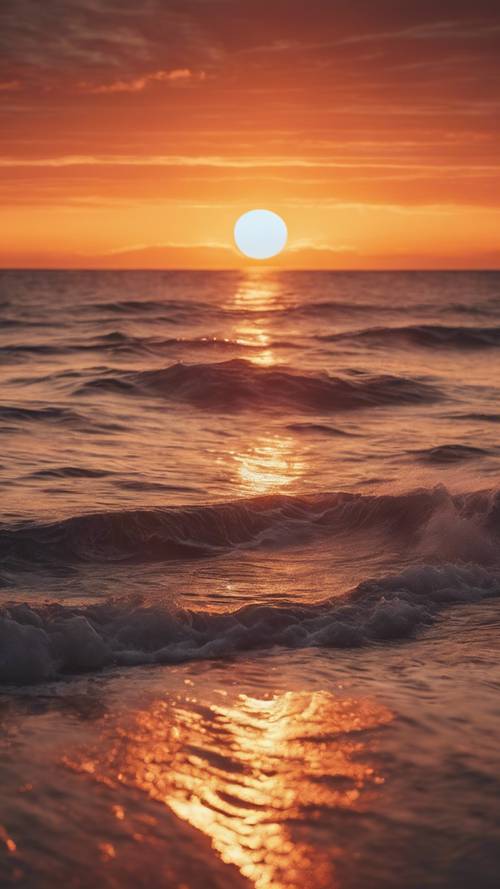 Vista deslumbrante de um oceano refletindo os tons ardentes de um pôr do sol de verão.
