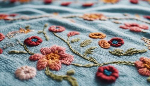 A hand embroidered Scandinavian floral pattern on a light blue woolen blanket.