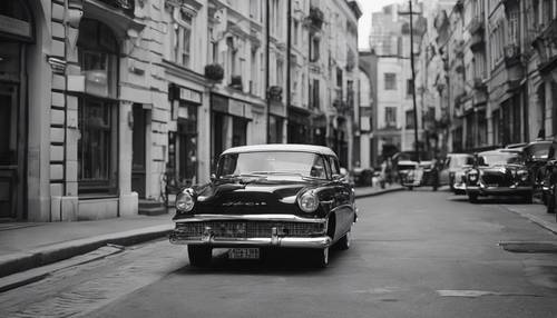 A black and white image of a preppy-styled classic car parked on a city street.