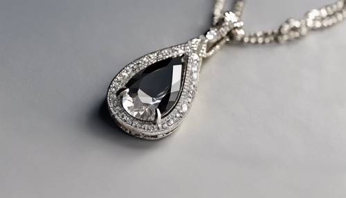 Um colar, com um pingente de uma lágrima de diamante negro enrolada em um deslumbrante diamante branco redondo.