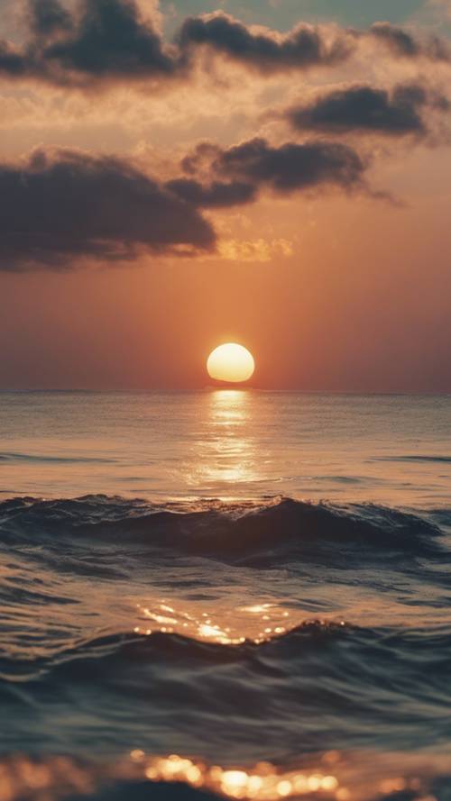 A magical view of the sun slowly sinking below the distant horizon of an open ocean.