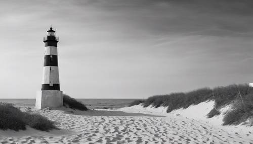 A panoramic view of a barren beach with a lonely lighthouse standing as a sentinel in black and white.